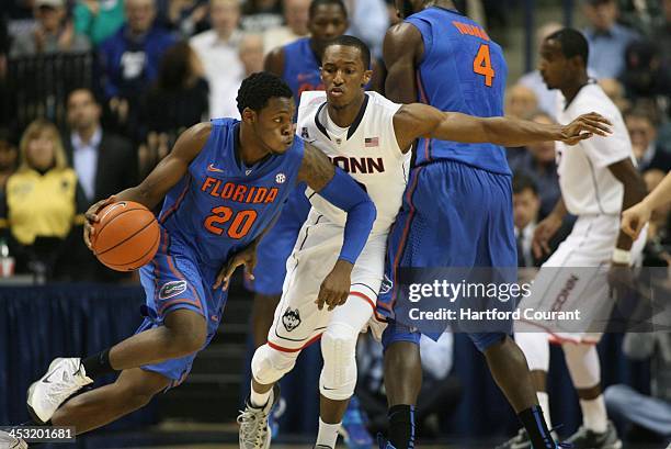 Florida Gators guard Michael Frazier tries to run a screen around Connecticut Huskies guard Lasan Kromath and Gators center Patric Young during the...