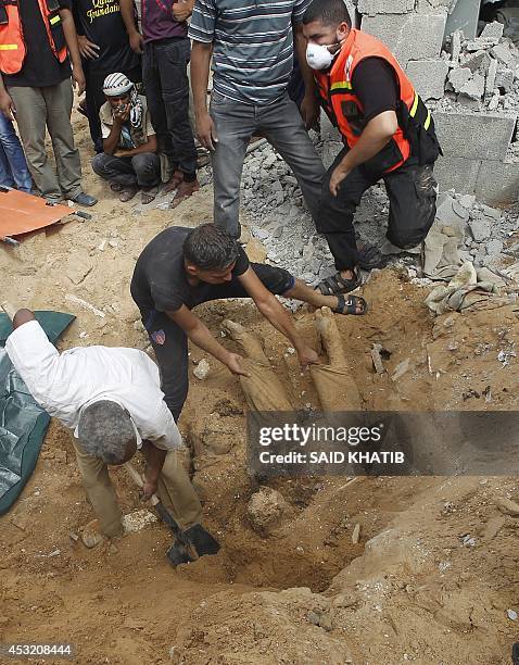 Rescue workers remove the body a Palestinian man from under the rubble following an earlier Israeli air strike in Rafah in the southern Gaza Strip,...