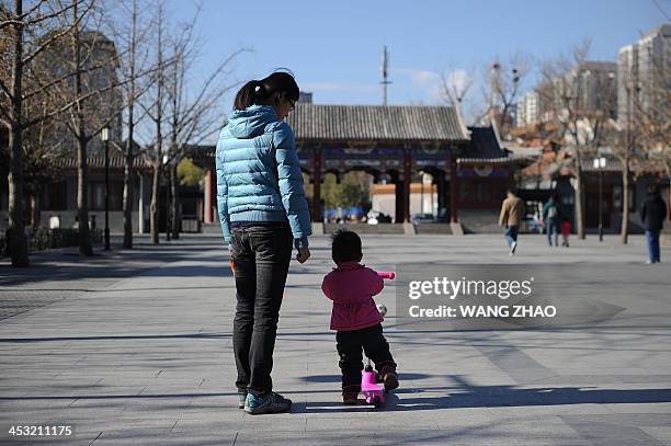 China-US-health-surrogacy,FEATURE by FELICIA SONMEZ A woman and child walk at a park in Beijing on November 26, 2013. For decades China has been a...