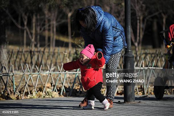 China-US-health-surrogacy,FEATURE by FELICIA SONMEZ A woman and child walk at a park in Beijing on November 26, 2013. For decades China has been a...