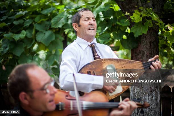Vasile Nica sings and plays a cobza at his place in Barboi village, 260 kilometers west from Bucharest, on June 27, 2014. AFP PHOTO / ANDREI...
