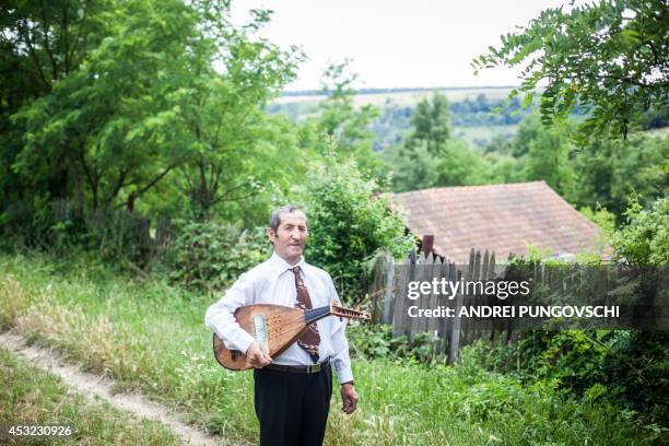 Vasile Nica poses with his cobza in Barboi village, 260 kilometers west from Bucharest, on June 27, 2014. AFP PHOTO / ANDREI PUNGOVSCHI