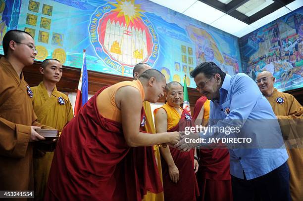 Buddhist monks from Hong Kong shake hands with former Philippine president and now Manila Mayor Joseph Estrada during a courtesy call and a press...