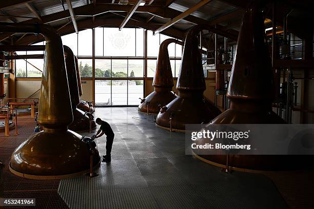 An employee checks a man-door on a copper pot still used to distil The Glenlivet single malt whisky, produced by Pernod Ricard SA, at the company's...