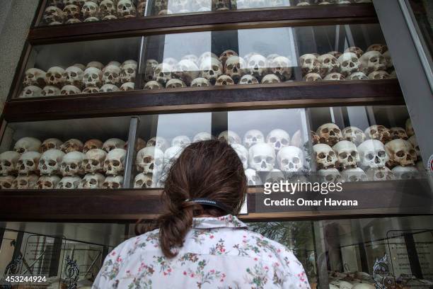 Young Cambodian woman looks at the main stupa in Choeung Ek Killing Fields, which is filled with thousands of skulls of those killed during the Pol...