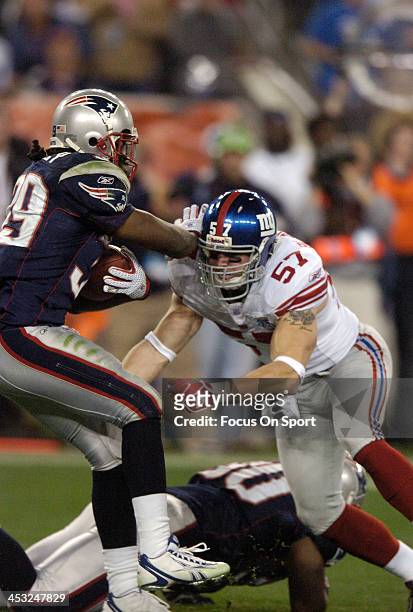 Chase Blackburn of the New York Giants tackles Laurence Maroney of the New England Patriots during Super Bowl XLII on February 3, 2008 at University...
