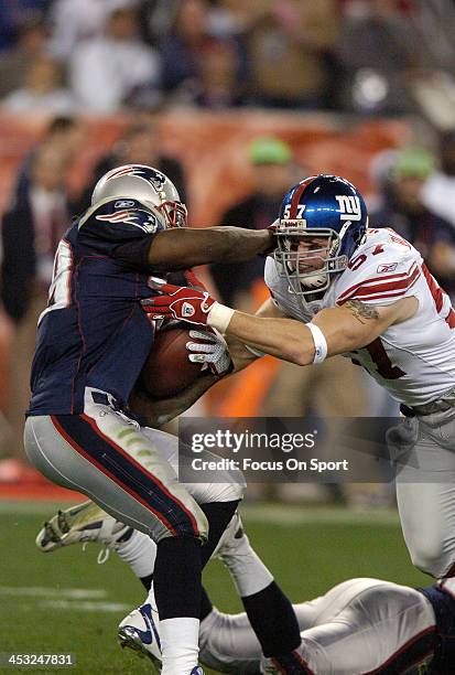 Chase Blackburn of the New York Giants tackles Laurence Maroney of the New England Patriots during Super Bowl XLII on February 3, 2008 at University...