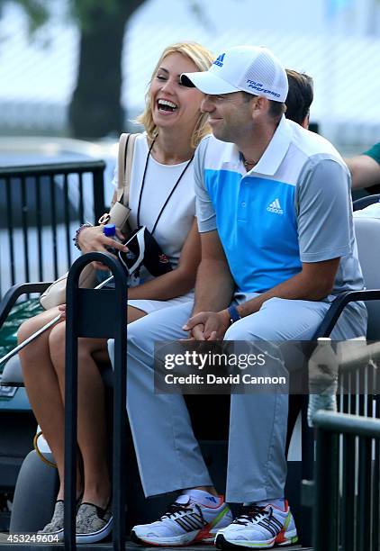 Sergio Garcia of Spain rides with girlfriend Katharina Boehm during a practice round prior to the start of the 96th PGA Championship at Valhalla Golf...