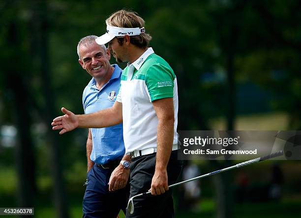 European Ryder Cup captain Paul McGinley talks with Victor Dubuisson of France during a practice round prior to the start of the 96th PGA...