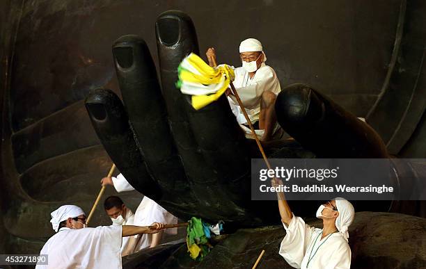 Buddhist monks clean dust off of the 15-meter-high Great Buddha's hand at the Todaiji Temple on August 7, 2014 in Nara, Japan. About 100 Buddhist...