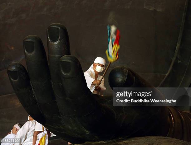 Buddhist monk cleans the dust off of the 15-meter-high Great Buddha's hand at the Todaiji Temple on August 7, 2014 in Nara, Japan. About 100 Buddhist...