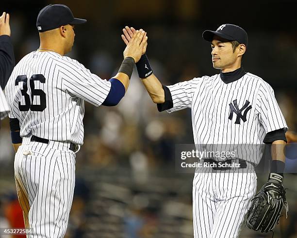 Carlos Beltran and Ichiro Suzuki of the New York Yankees high five each other after defeating the Detroit Tigers 5-1 in a MLB baseball game at Yankee...