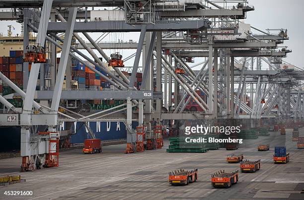 Automated guided vehicles transport shipping containers on the dockside as ship-to-shore cranes operate at Europe Container Terminals BV Delta...
