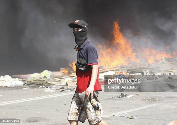 An activist holds a molotov cocktail in front of a burning barricade at Independence Square, also known as the Maidan, during a protest against the...