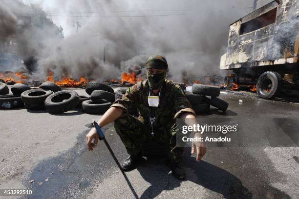 An activist sits in front of a burning barricade at Independence Square, also known as the Maidan, during a protest against the local authorities'...