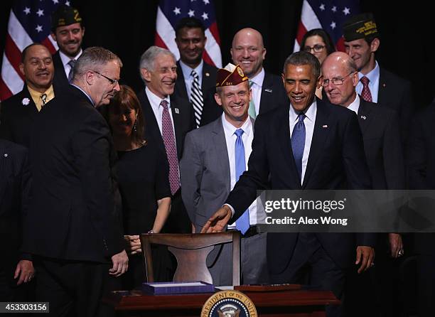 President Barack Obama takes his seat to sign H.R. 3230 as representatives from veterans groups look on August 7, 2014 at Wallace Theater in Fort...