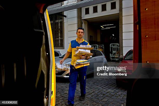 Postal worker puts some packages in a vehicle in Rio de Janeiro, Brazil, on Thursday, Aug. 7, 2014. Brazilian postal workers became unlikely victims...