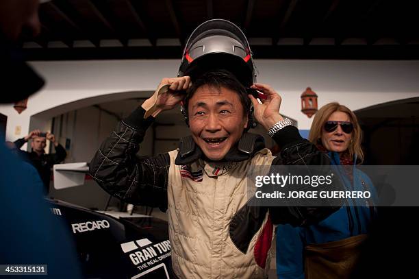 Polyphony Digital Inc president and creator of the series best selling PlayStation Gran Turismo Japanese Kazunori Yamauchi reacts as he puts a helmet...