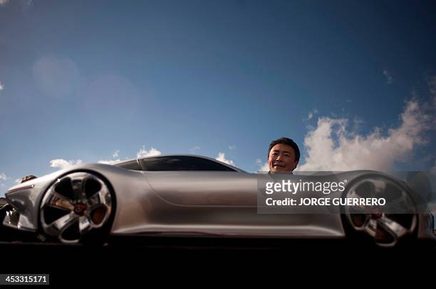 Polyphony Digital Inc president and creator of the series best selling PlayStation Gran Turismo Japanese Kazunori Yamauchi poses behind a model car...