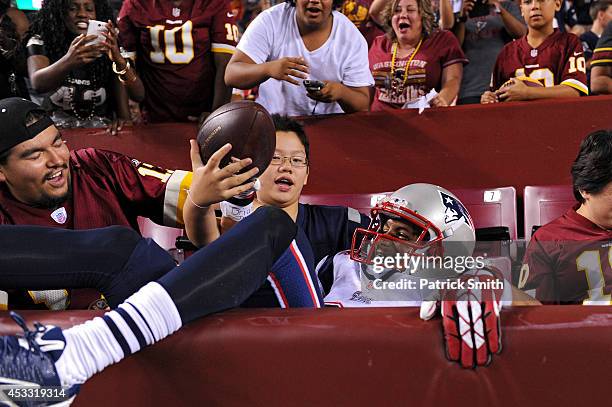 Fans try to grab the ball from wide receiver Brian Tyms of the New England Patriots after he scored a touchdown in the fourth quarter against the...