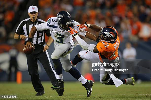 Quarterback Russell Wilson of the Seattle Seahawks draws a face mask penalty as he stiff-arms strong safety T.J. Ward of the Denver Broncos during...