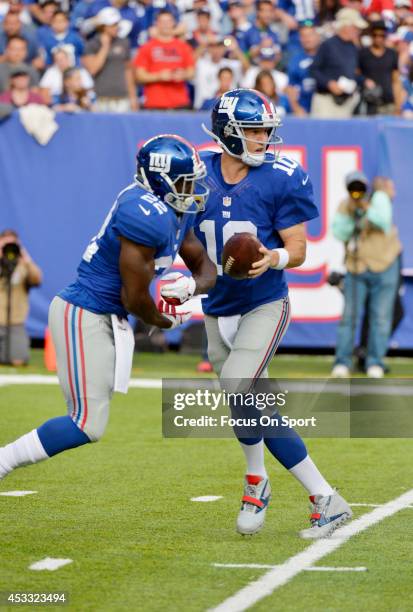 Eli Manning of the New York Giants drops back to pass, faking the handoff to David Wilson against the Denver Broncos during an NFL football game at...