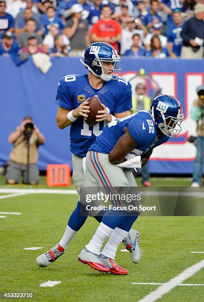 Eli Manning of the New York Giants drops back to pass, faking the handoff to David Wilson against the Denver Broncos during an NFL football game at...