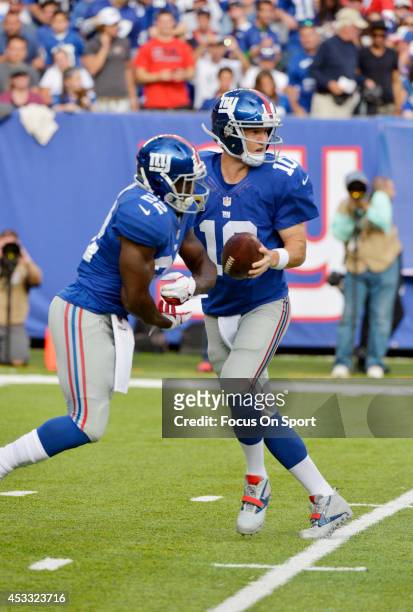 Eli Manning of the New York Giants drops back to pass, faking the handoff to David Wilson against the Denver Broncos during an NFL football game at...