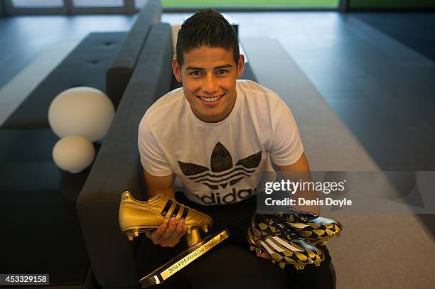 Footballer James Rodriguez holds his adidas Golden Boot Trophy and a pair of adiZero boots at Real Madrid's Valdebebas in recognition of scoring the...