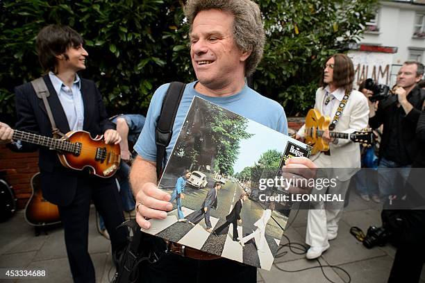 Man holds a copy of the Beatles album "Abbey Road" as the cast of the musical "Let It Be" preapre to perform near famous Abbey Road zebra crossing in...