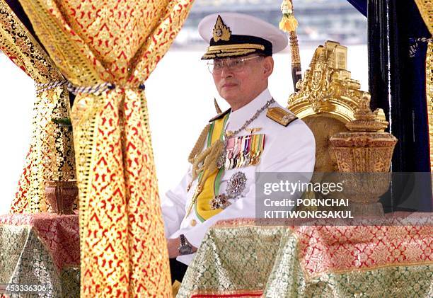 Thailand's King Bhumibol Adulyadej sits in a barge in front of a colourful water-borne on the river Chao Phraya in Bangkok 04 November 1999. The...