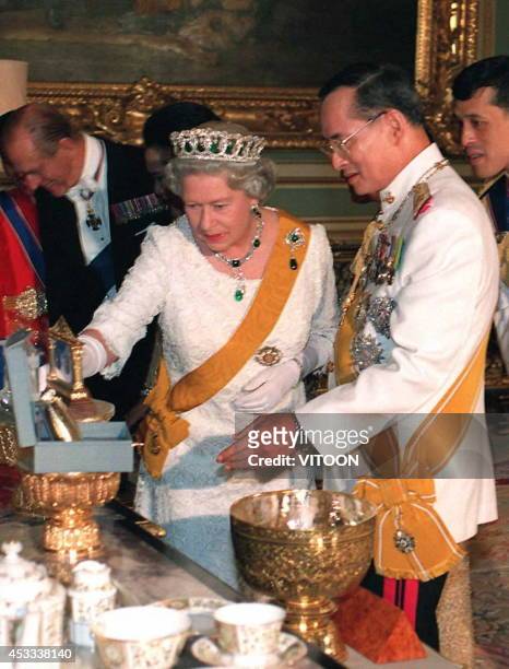 Britain's Queen Elizabeth II looks at gifts presented to her by Thai King Bhumibol Adulyadej before a state banquet held in her honour at the Grand...