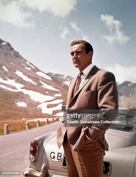 Actor Sean Connery poses as James Bond next to his Aston Martin DB5 in a scene from the United Artists film 'Goldfinger' in 1964