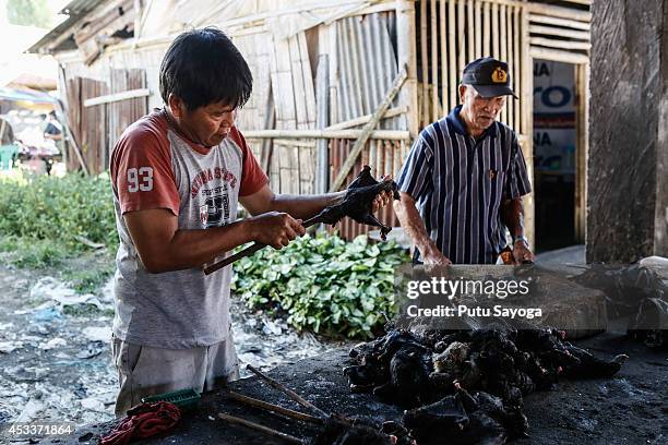 Men prepare to roast bats at Langowan traditional market on August 9, 2014 in Langowan, North Sulawesi. The Langowan traditional market is famous for...