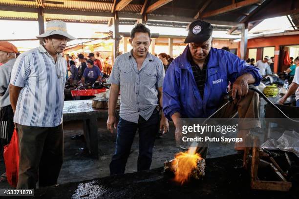 Consumers watch a man roasting snake at Langowan traditional market on August 9, 2014 in Langowan, North Sulawesi. The Langowan traditional market is...