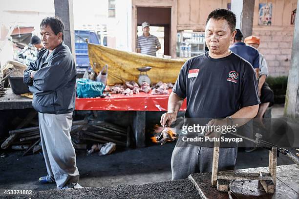 Man roasts a bat at Langowan traditional market on August 9, 2014 in Langowan, North Sulawesi.The Langowan traditional market is famous for selling a...