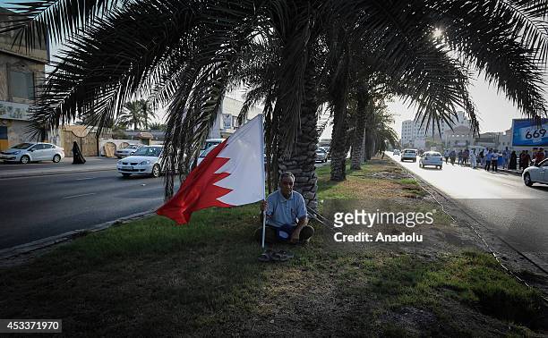 Bahraini opponent holds national flag of Bahrain during an anti-government protest in Manama, Bahrain on August 8, 2014.