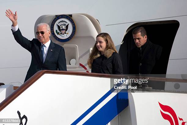 Vice President Joe Biden waves as he walks out of Air Force Two with his granddaughter Finnegan Biden and son Hunter Biden at the airport December 4,...