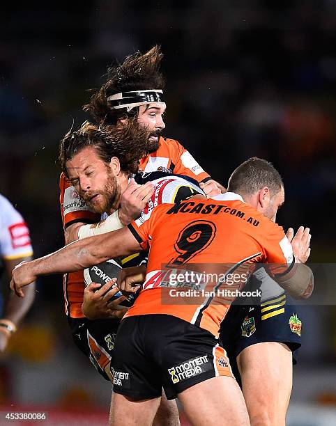 Ashton Sims of the Cowboys is tackled by Aaron Woods and Robbie Farah of the Tigers during the round 22 NRL match between the North Queensland...