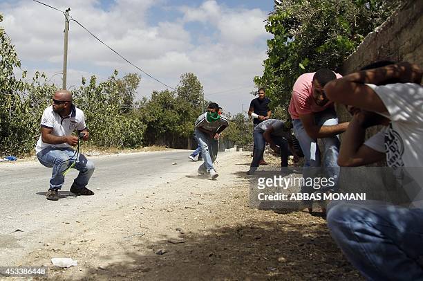 Palestinian demonstrators take cover during clashes with Israeli soldiers at the entrance of the Jewish settlement of Psagot near the Palestinian...