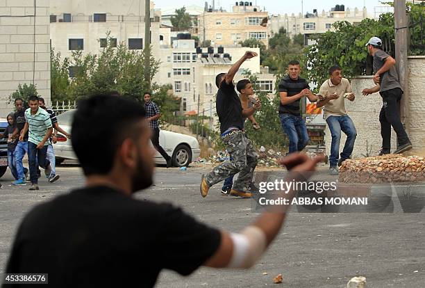 Palestinian demonstrators hurl rocks at Israeli soldiers during clashes at the entrance of the Jewish settlement of Psagot near the Palestinian town...