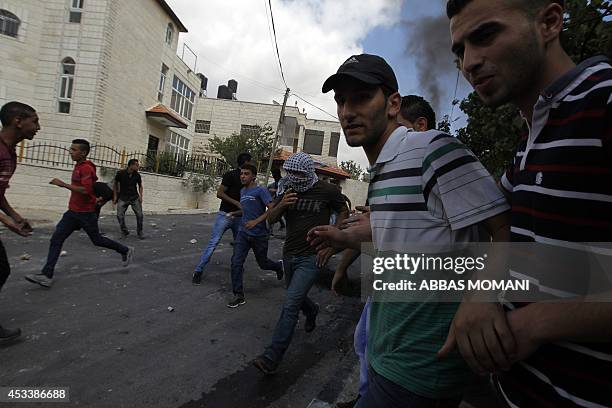 Palestinian demonstrators take cover during clashes with Israeli soldiers at the entrance of the Jewish settlement of Psagot near the Palestinian...