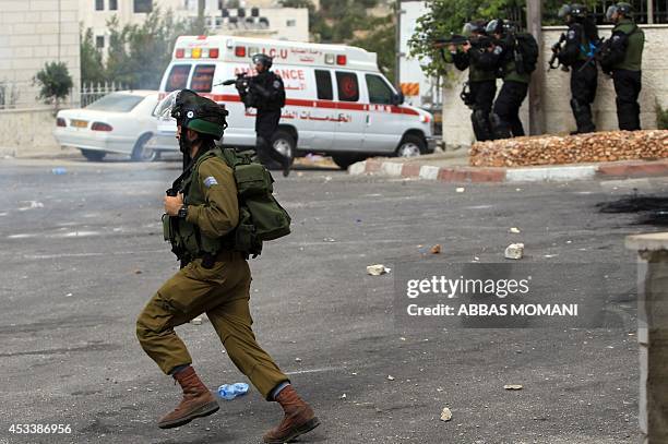 Israeli soldiers take position during clashes with Palestinian demonstrators at the entrance of the Jewish settlement of Psagot near the Palestinian...
