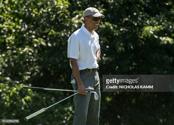 President Barack Obama smiles as he watches his golfing partners putt on the first green while playing at the Farm Neck Golf Club at Martha's...