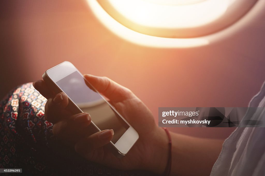 Frau mit smartphone im Flugzeug, während Flug