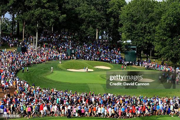 Rory McIlroy of Northern Ireland hits his second shot on the 14th hole as a gallery of patrons look on during the third round of the 96th PGA...