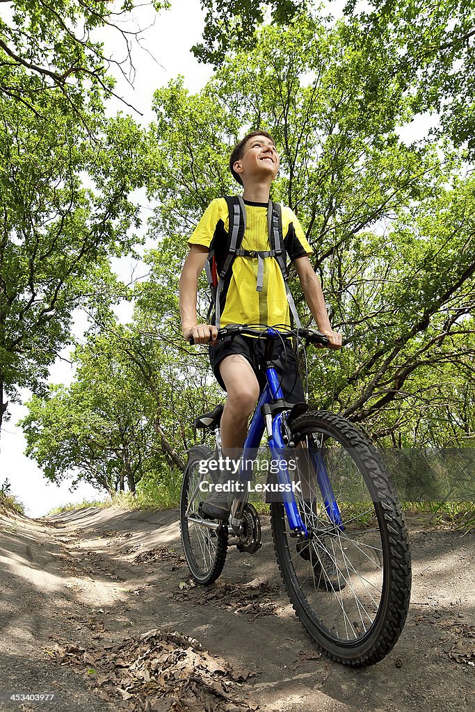Adolescente su una bicicletta in viaggio nella foresta