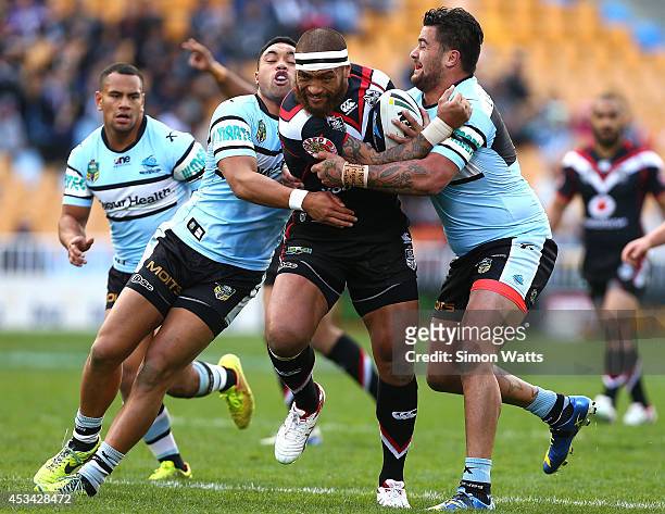 Manu Vatuvei of the Warriors looks to beat the tackle of Andrew Fifita and Tupou Sopoaga of the Sharks during the round 22 NRL match between the New...