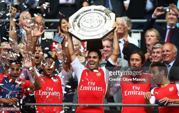 Captain Mikel Arteta of Arsenal holds up the trophy alongside team-mates Alex Oxlade-Chamberlain Tomas Rosicky and Santi Cazorla after winning the FA...