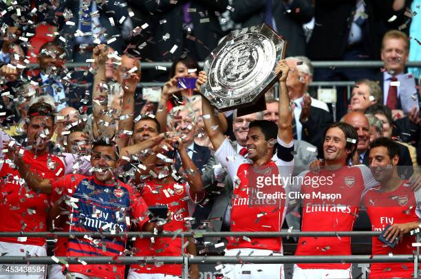 Captain Mikel Arteta of Arsenal holds up the trophy alongside team-mates Tomas Rosicky and Santi Cazorla after winning the FA Community Shield match...